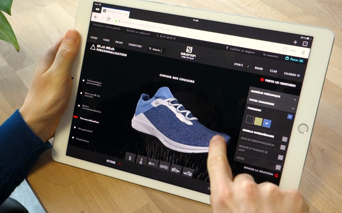 Picture of a customer interacting on the Salomon S Lab ME:sh customization webpage on an Ipad. Here the consumer can do a complete customization of every part (twinskin, midsole, lace armor & webbing, laces) of the running shoes so that he can design their perfect shoe according to their morphology, running style/frequency and own personal taste.