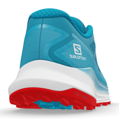 Vue arrière d'une chaussure Salomon Ultra Glide. Les couleurs sont le bleu ciel pour la partie textile et le blanc et le rouge pour la semelle. Le logo Salomon est imprimé sur le côté droit. On peut voir les crampons sur la semelle.