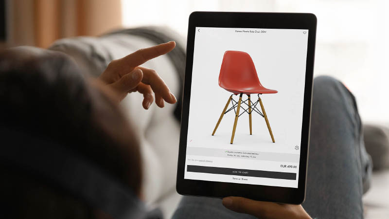 Vitra Eames Chair Configurator on Ipad A customer is lying on a sofa using an Emersya 3D configurator to visualize and configure the different options for the Vitra eames chair on his iPad.